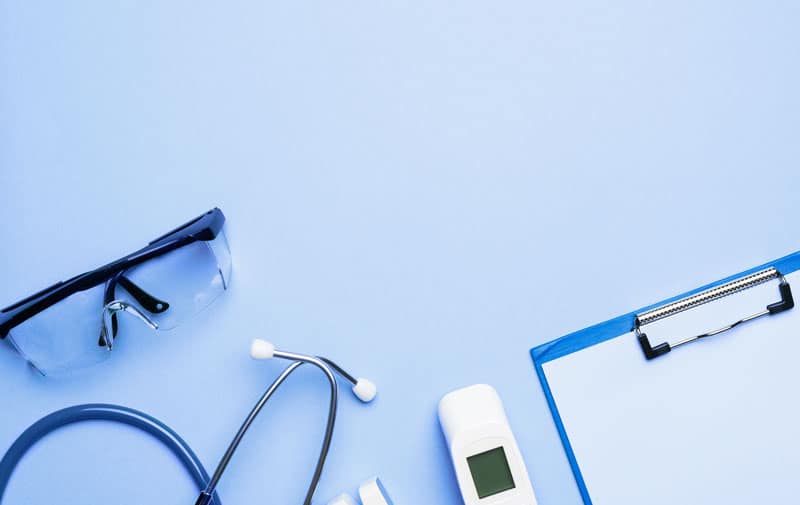 Schutzbrille, Stethoskop, Fieberthermometer und Klemmbrett