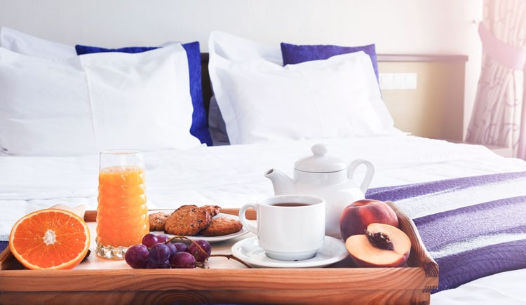 Hotelbett mit Frühstückstablett am Fußende